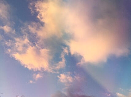 a photo of clouds in front of a blue sky. the cloud is slighty rainbpw and the photo is tinted pale red